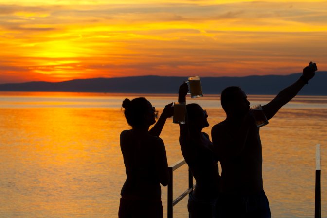 Fonyód, 2015. augusztus 28.  Kezükben sörös korsókat tartó fiatalok fényképezik magukat egy okostelefonnal naplementekor a Balaton partján Fonyódnál 2015. augusztus 28-án. Másodfokú hõségriasztást ad ki augusztus 29-én 0 órától szeptember 1-jén éjfélig az országos tisztifõorvos, idén ötödik alkalommal. MTI Fotó: Varga György